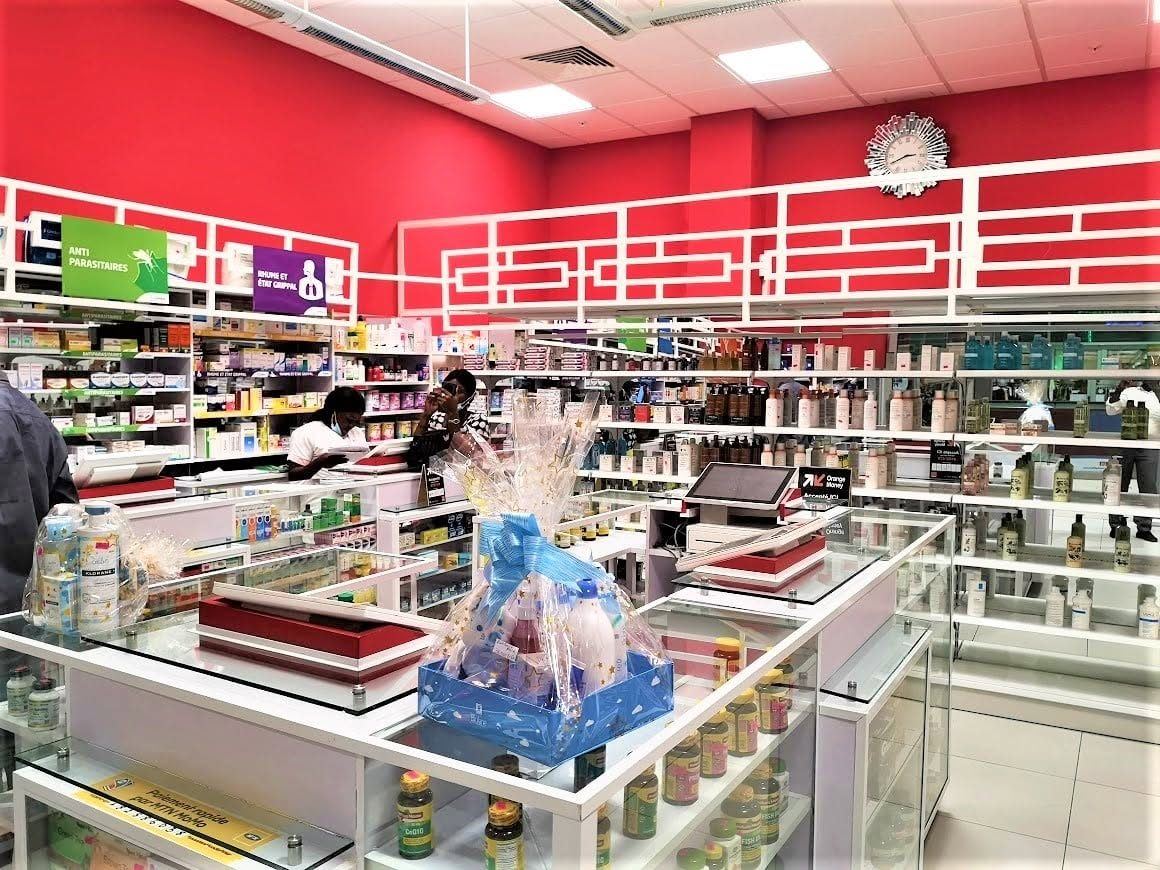 Intérieur de Pharmacie Riviera : murs rouges, rayons et comptoirs blancs
